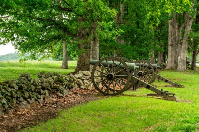 old cannons in a park with stone wall and lush greenery